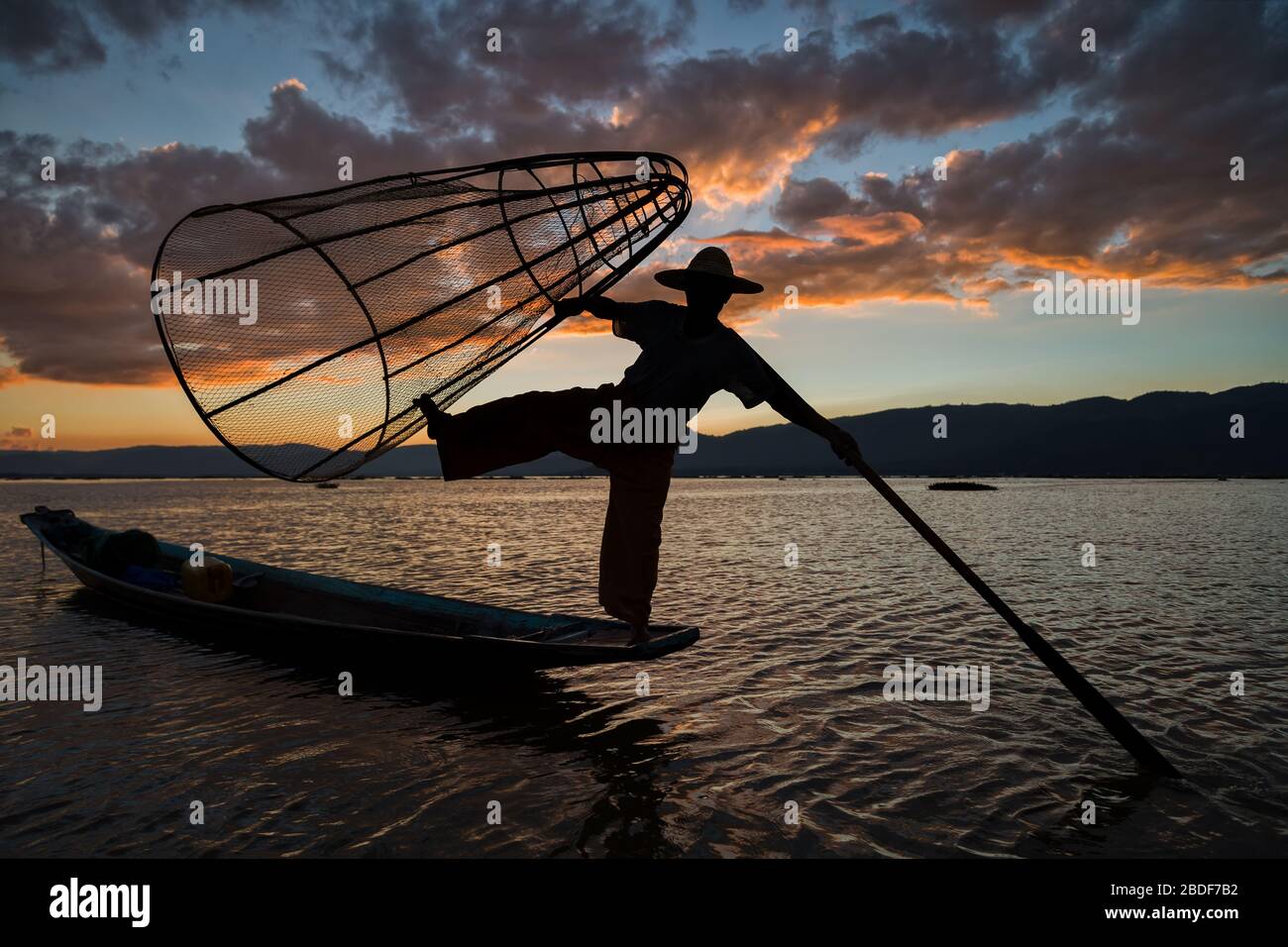 Pescatore Intha posa con reti conica al tramonto, Lago Inle nel Nyaungshwe Township parte delle colline Shan in MYANMAR Birmania Foto Stock