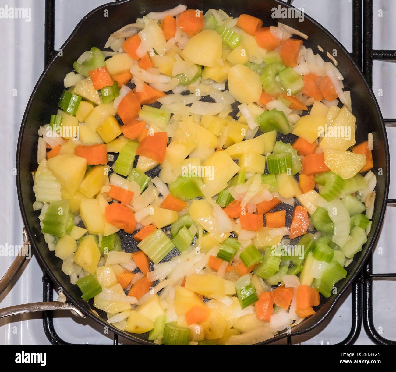 Soffriggere le verdure in una padella su una stufa prima di stufare Foto Stock