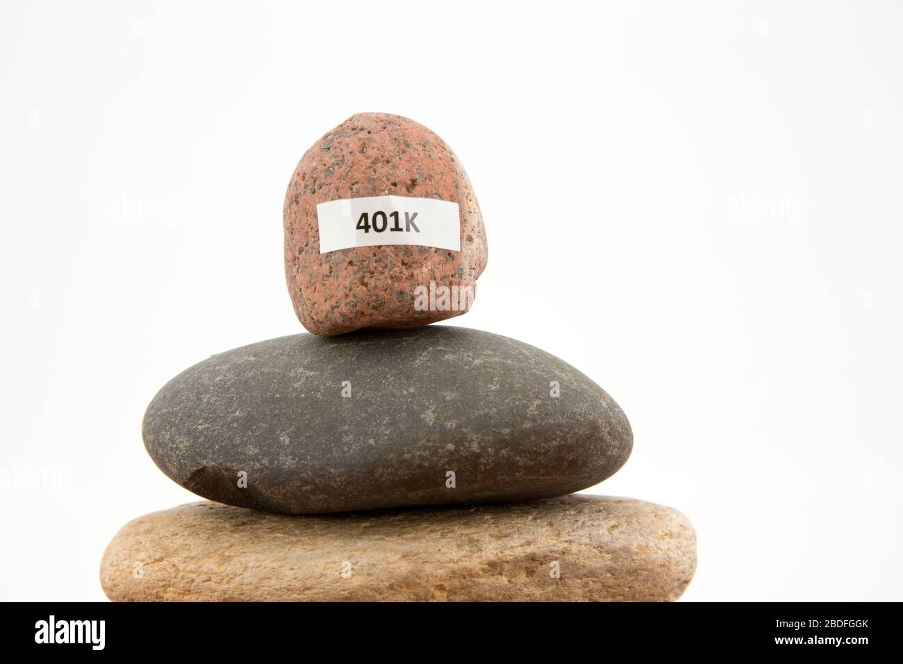 L'immagine concettuale della pietra 401K accuratamente bilanciata riflette una pericolosa crisi economica e il pericolo finanziario personale Foto Stock