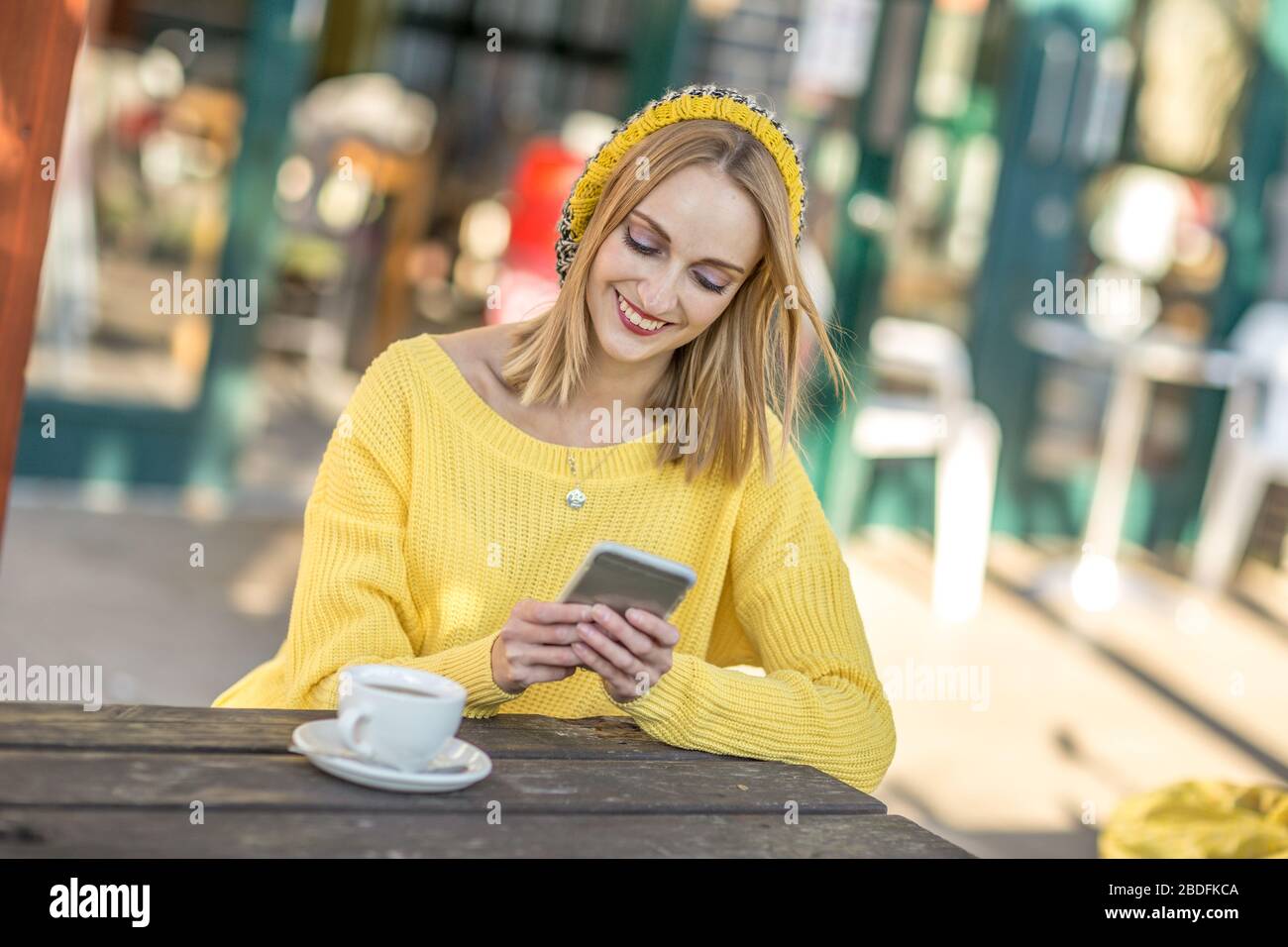 giovane donna al caffè che invia un messaggio di testo Foto Stock