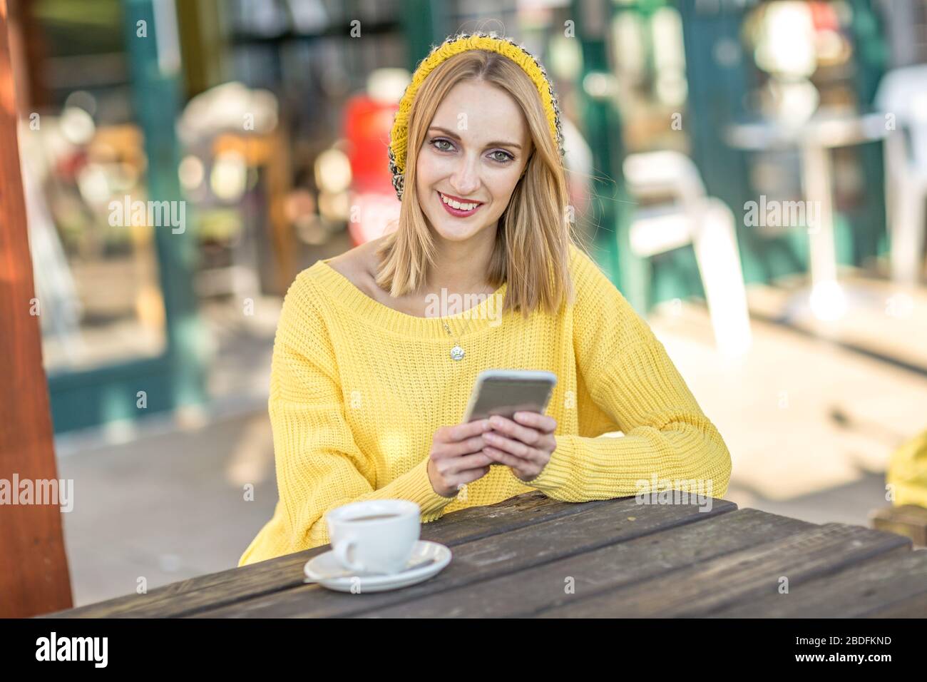 Giovane donna seduta al di fuori di un coffee shop Foto Stock