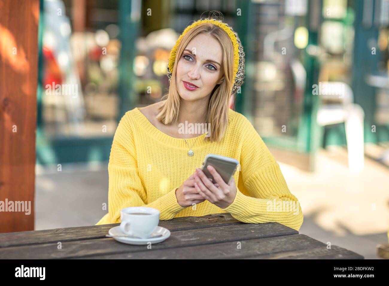 giovane donna seduta fuori di un caffè che pensa Foto Stock