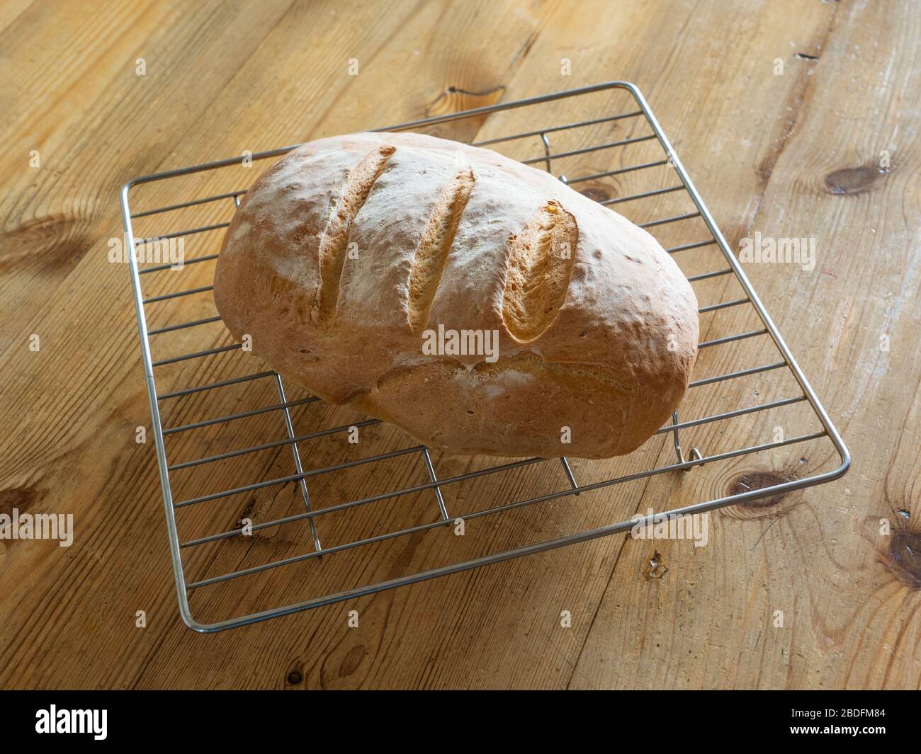 Appena cotto a casa fatto Bloomer pane su una griglia di raffreddamento filo posto su un tavolo di legno. Foto Stock