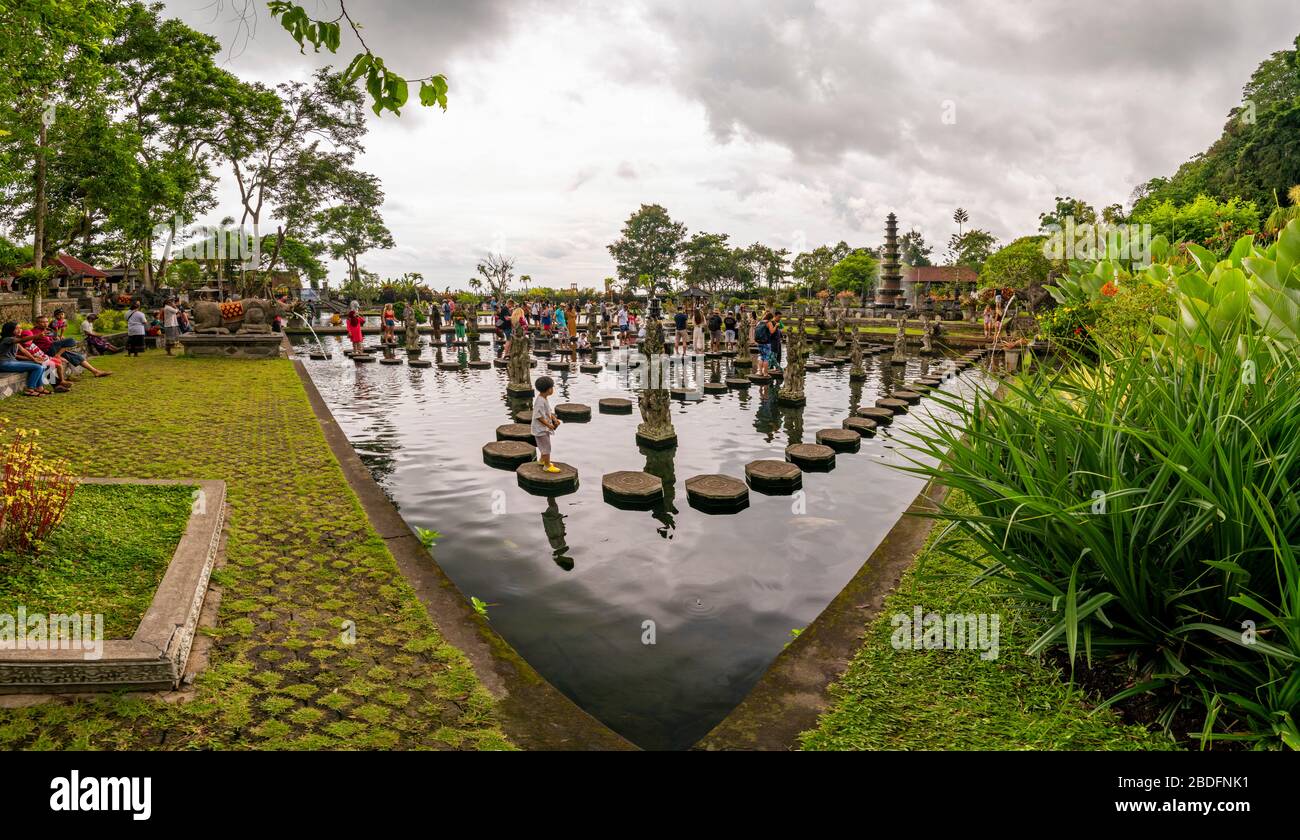 Vista orizzontale dei turisti che camminano sulle pietre a passo al palazzo d'acqua di Tirta Gangga a Bali, Indonesia. Foto Stock