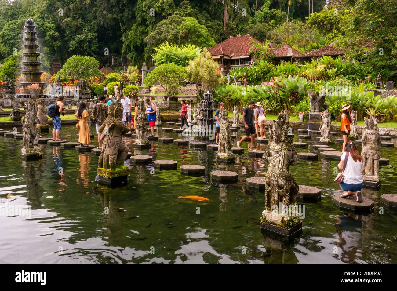 Vista orizzontale dei turisti che camminano sulle pietre a passo al palazzo d'acqua di Tirta Gangga a Bali, Indonesia. Foto Stock