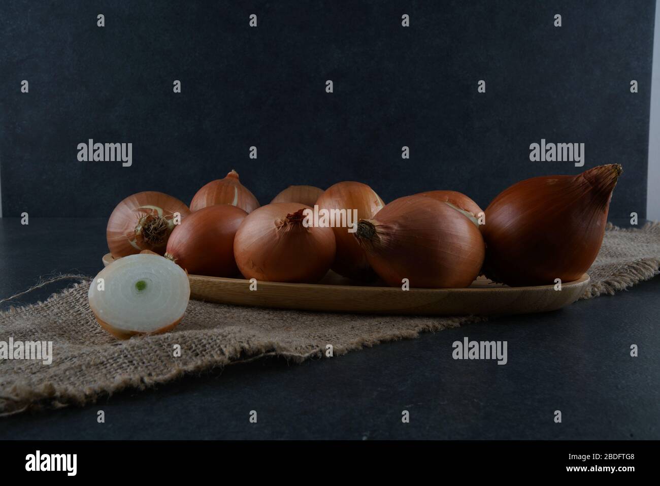 Un gruppo di cipolle su sfondo scuro Foto Stock