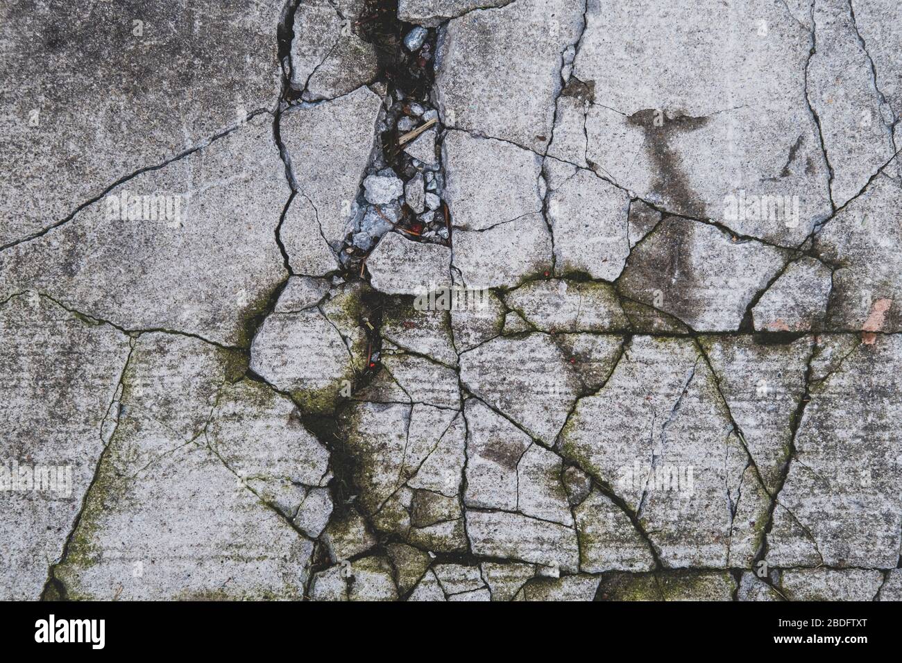 Dettaglio del marciapiede in calcestruzzo fratturato e fessurato Foto Stock