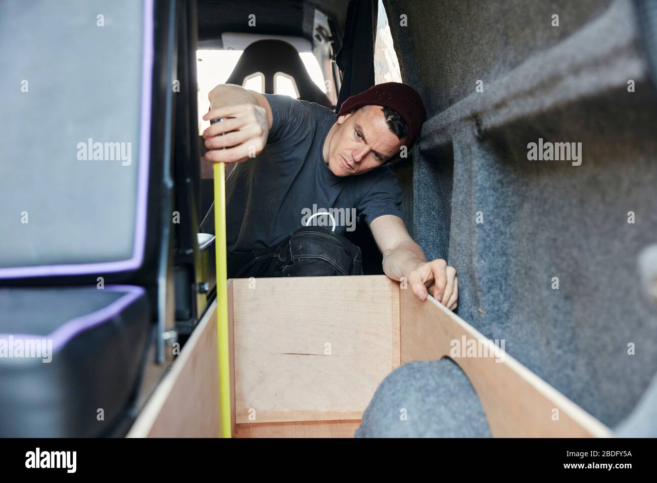 Uomo che usa il metro a nastro in furgone Foto Stock