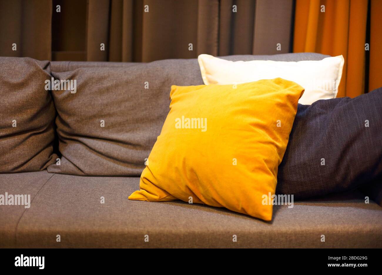 Interno soggiorno con divano grigio e cuscini gialli. Sfondo accogliente Foto Stock