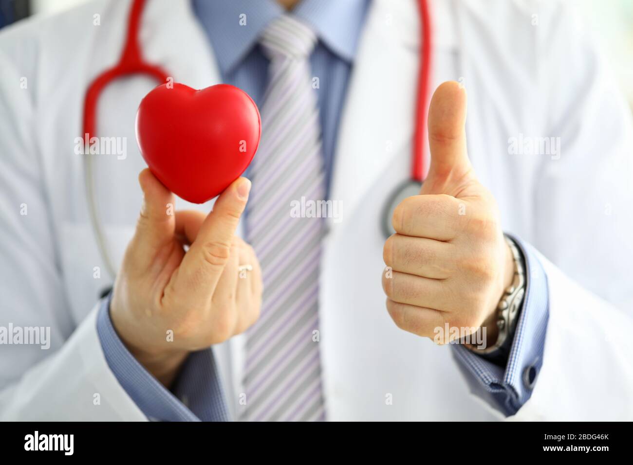 Medico di medicina maschile in tenere rosso giocattolo cuore e mostrare OK Foto Stock