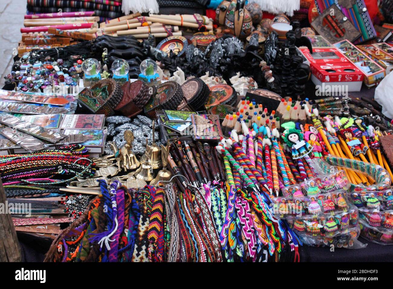 Un tavolo pieno di souvenir colorati, penne, gioielli, magneti, carte, strumenti musicali nel mercato Pisac in Perù Foto Stock