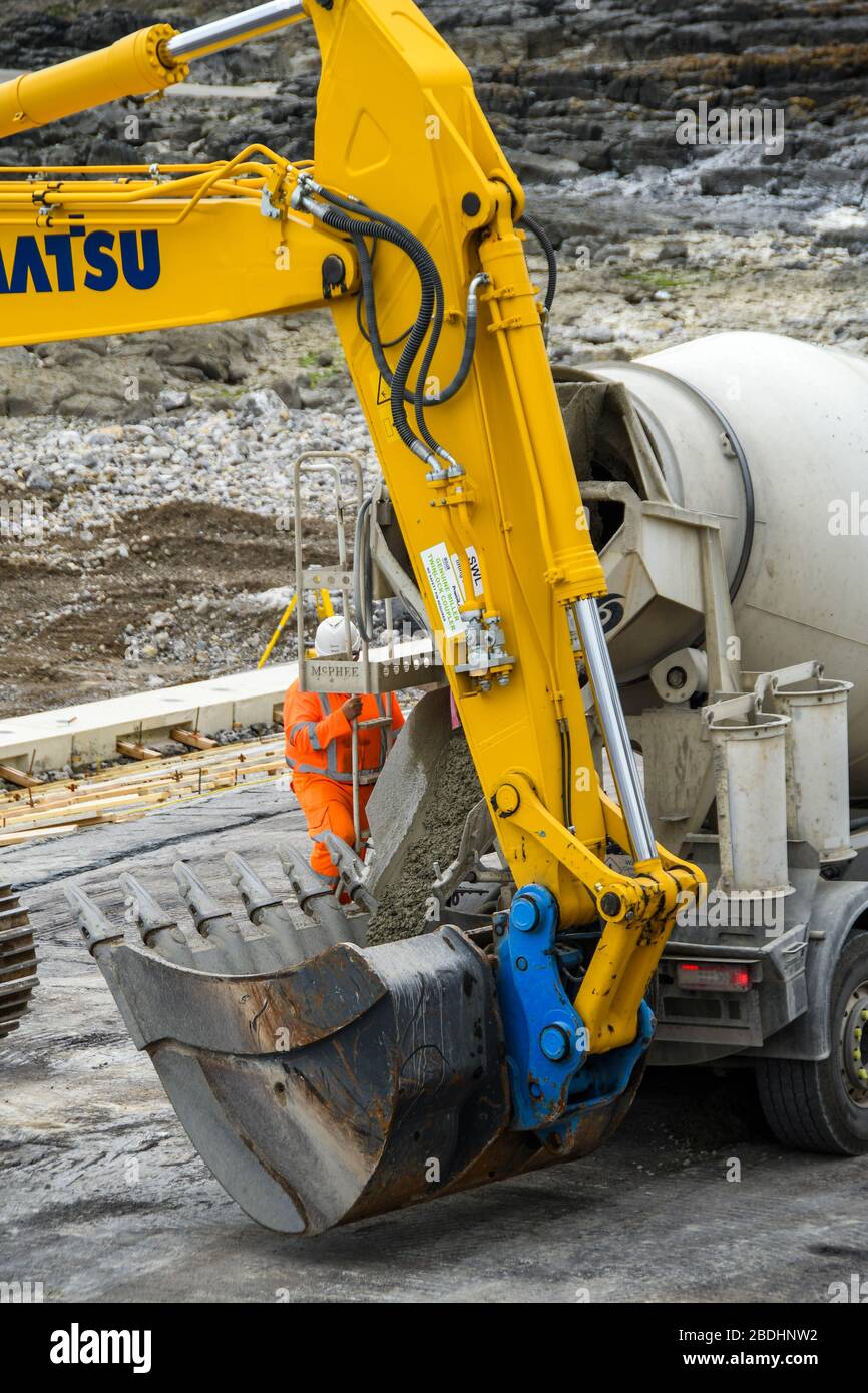 PORTHCATWL, GALLES - GIUGNO 2018: Betoniera che scarica calcestruzzo preconfezionato nella benna di un escavatore per impieghi pesanti per le difese marine Foto Stock