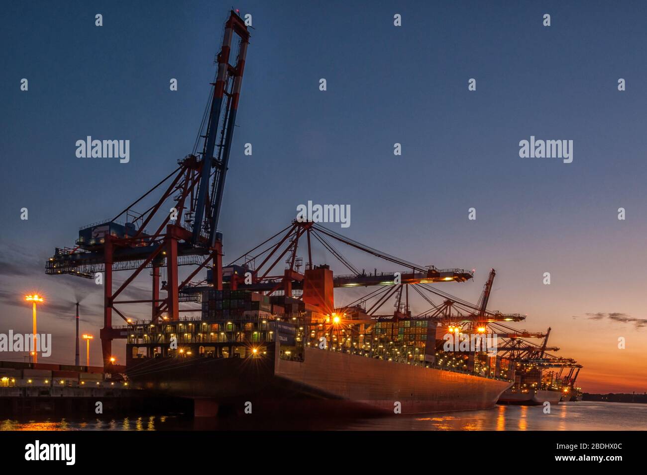 Autogru container nel Waltershofer Hafen di Amburgo al tramonto Foto Stock