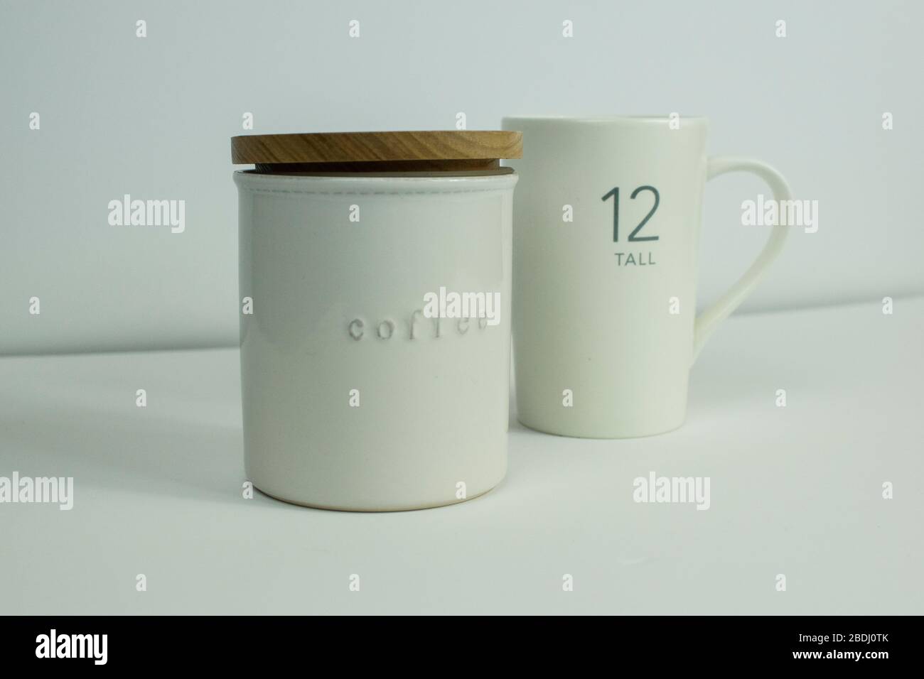 Contenitore per caffè bianco con parte superiore in legno e tazza da caffè bianca su sfondo bianco Foto Stock