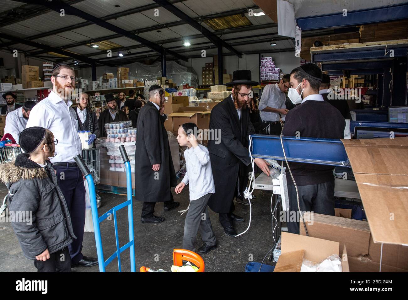 Gli ebrei ultra-ortodossi nella Comunità ebraica di Stamford Hill hanno accodato per le disposizioni in un magazzino prima delle celebrazioni della Pasqua di settimana, Londra Foto Stock