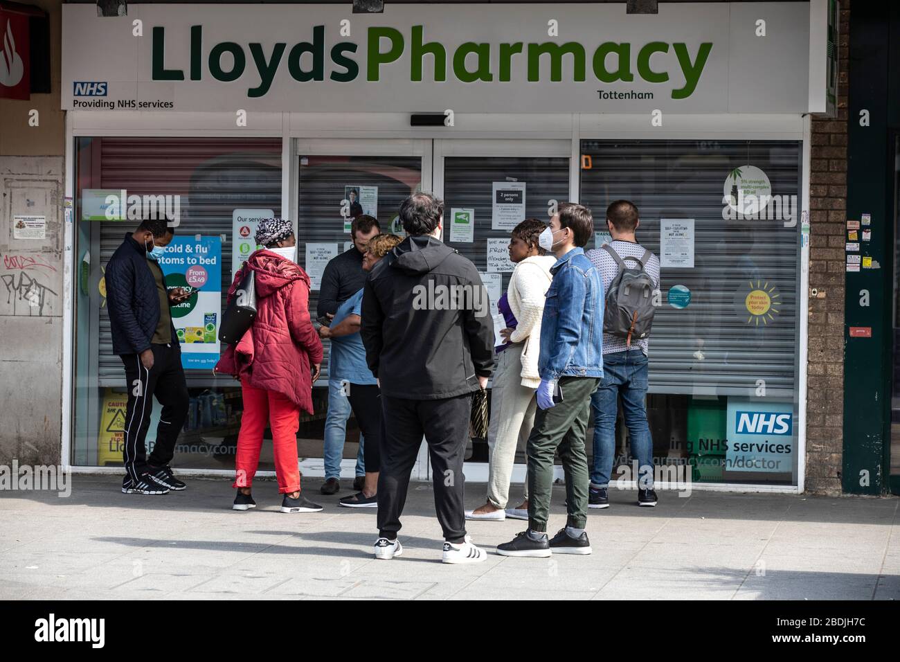 Le persone si accodano al di fuori di una Lloyds Pharmacy a Tottenham, North London, durante il blocco COVID-19, Londra, Inghilterra, Regno Unito Foto Stock