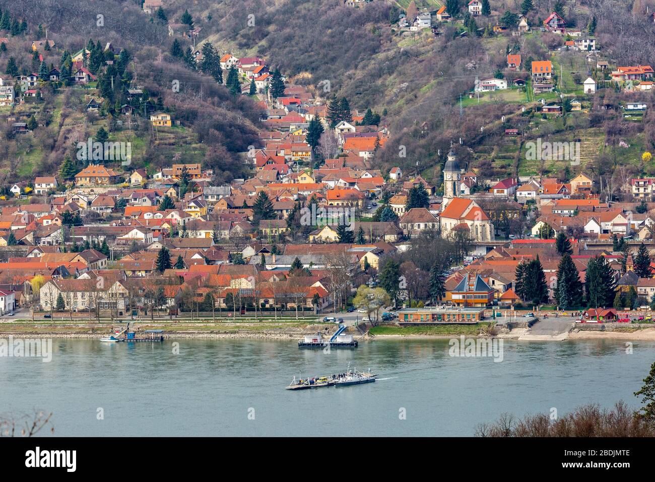 Bella vista della piccola città Nagymaros in altopiani sul lato del fiume Danubio, Ungheria. Un piccolo traghetto attraversa il fiume Foto Stock