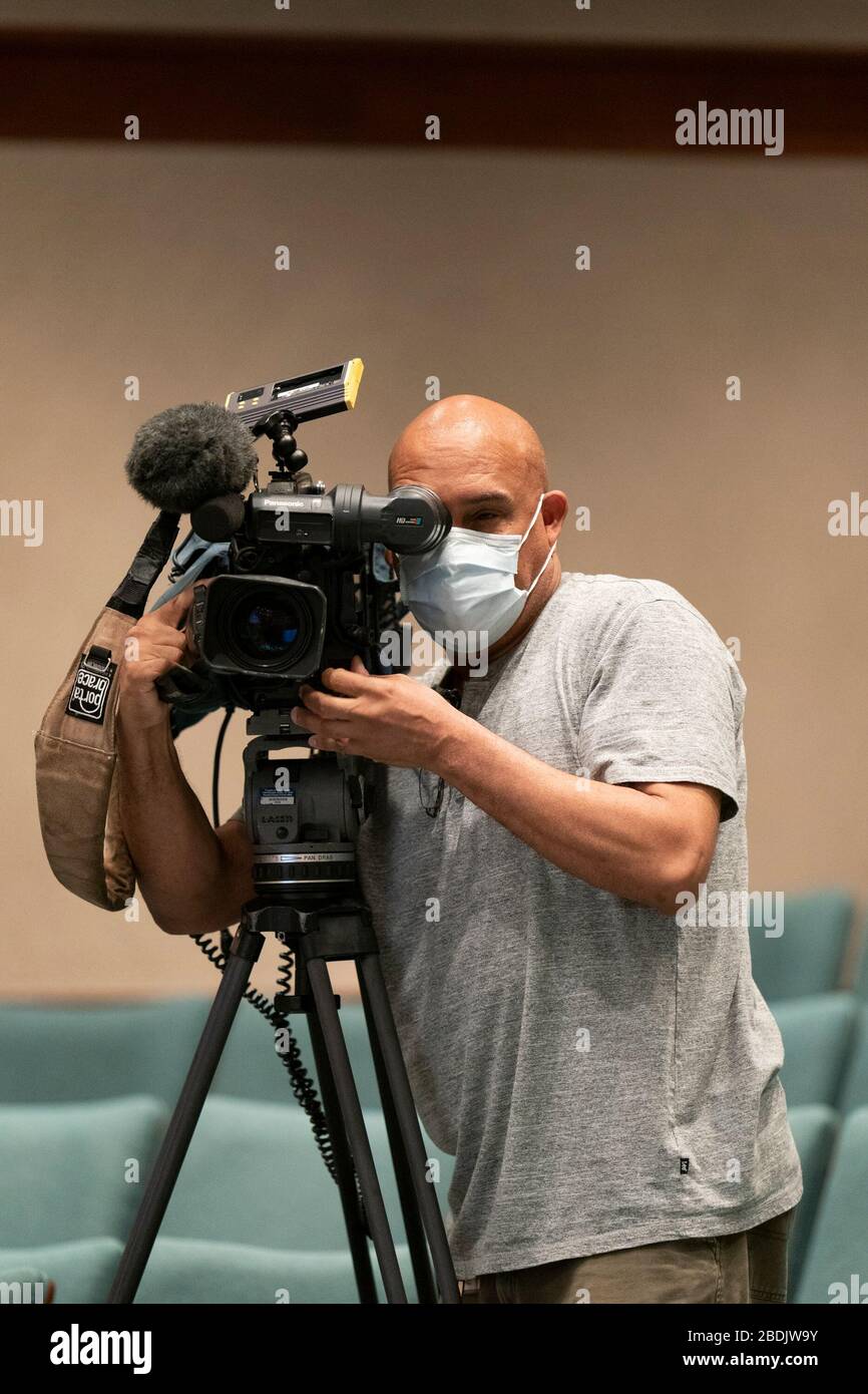 Un fotografo della stampa del Texas Capitol indossa una maschera facciale mentre registra video mentre il governatore Greg Abbott fornisce informazioni sull'aumento della produzione volontaria di maschere facciali e schermi facciali da parte delle aziende del Texas per soddisfare la crescente domanda nella lotta contro l'epidemia di coronavirus. Foto Stock