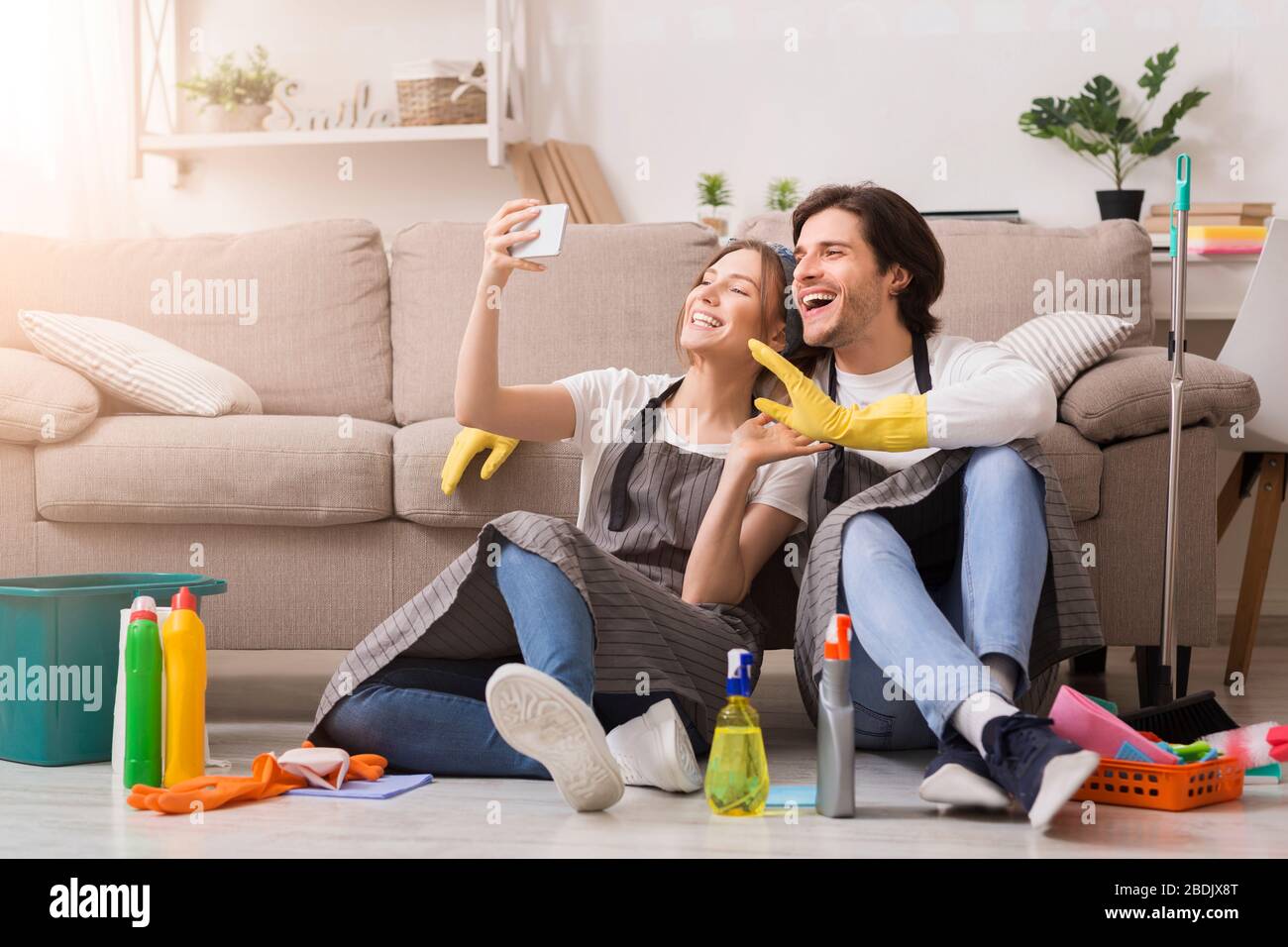 Giovane coppia sorridente che prende il selfie sullo smartphone dopo la primavera-pulizia appartamento Foto Stock