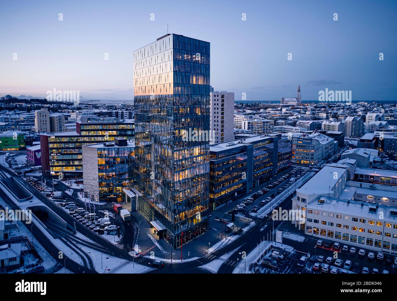 Dall'alto delle strade innevate del quartiere contemporaneo della città, con alti edifici illuminati e strade vuote nella mattina d'inverno in Islanda Foto Stock