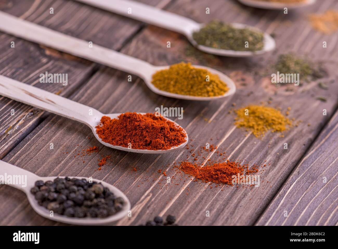 Assortimento di spezie colorate in i cucchiai di legno. Foto Stock