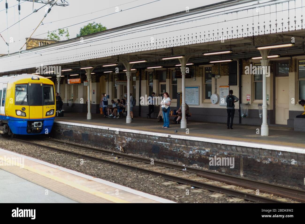 I treni sotterranei e terrestri sono parte integrante del sistema di transito Englands, come questi passeggeri che attendono alla stazione di Camden Road a Londra. Foto Stock
