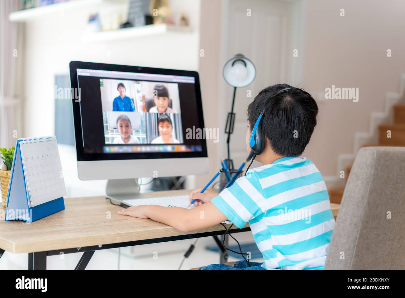 Asian boy studente video conferenza e-learning con insegnante e compagni di classe sul computer in soggiorno a casa. Homeschooling e apprendimento a distanza, onl Foto Stock