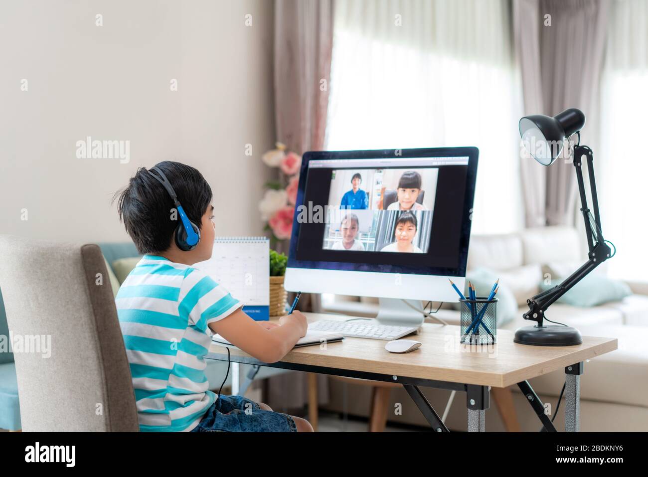 Asian boy studente video conferenza e-learning con insegnante e compagni di classe sul computer in soggiorno a casa. Homeschooling e apprendimento a distanza, onl Foto Stock