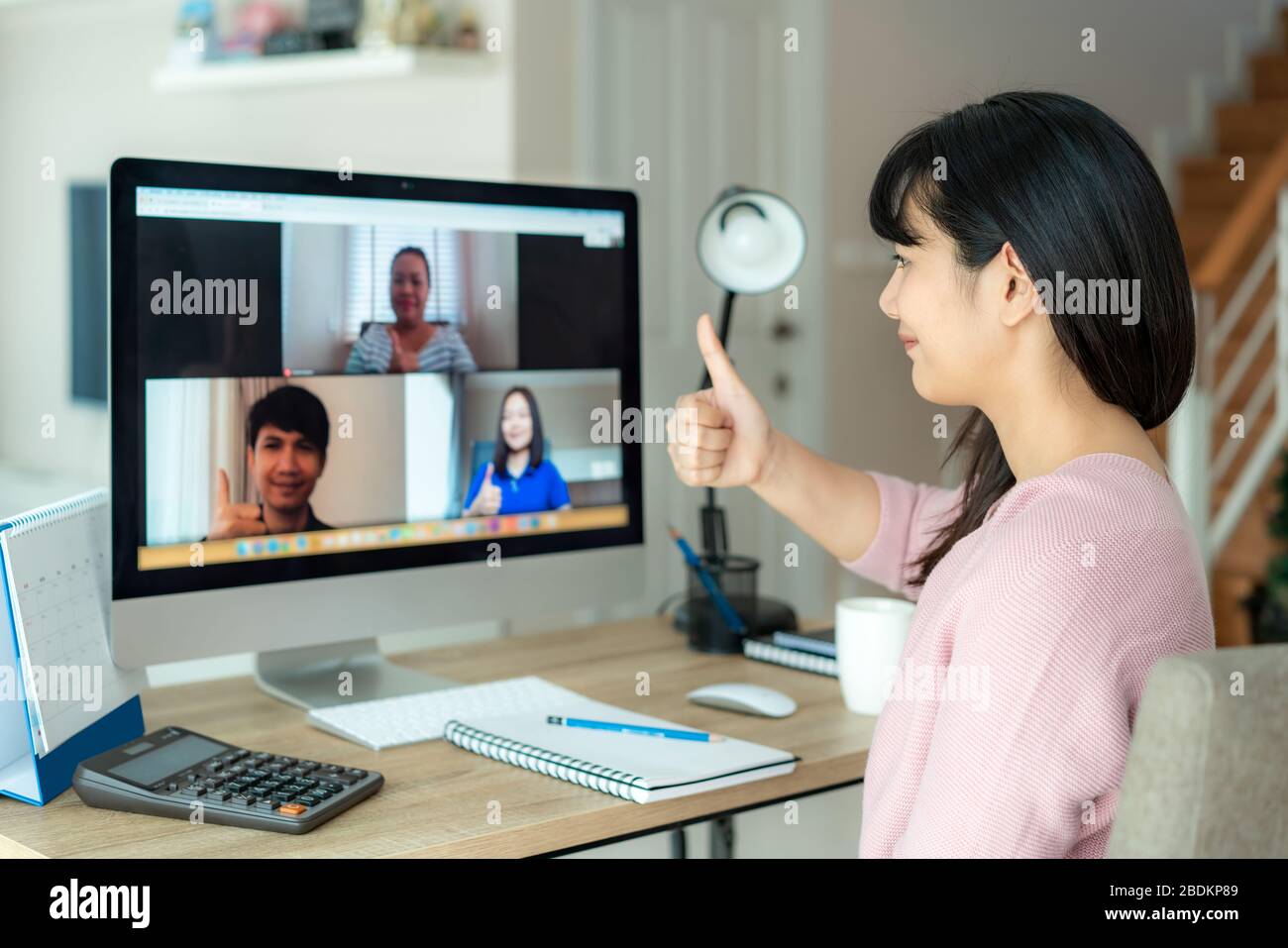 La donna asiatica d'affari si mette in piedi ai suoi colleghi circa il programma nella video conferenza. Team multietnico di affari che utilizza il computer per una riunione on-line in vide Foto Stock