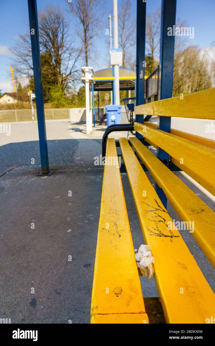 N. Vancouver - 7 aprile 2020: Guanti usati per uso medico scartati tra le doghe del sedile alla stazione degli autobus pubblici durante la pandemia Coronavirus Covid-19 Foto Stock