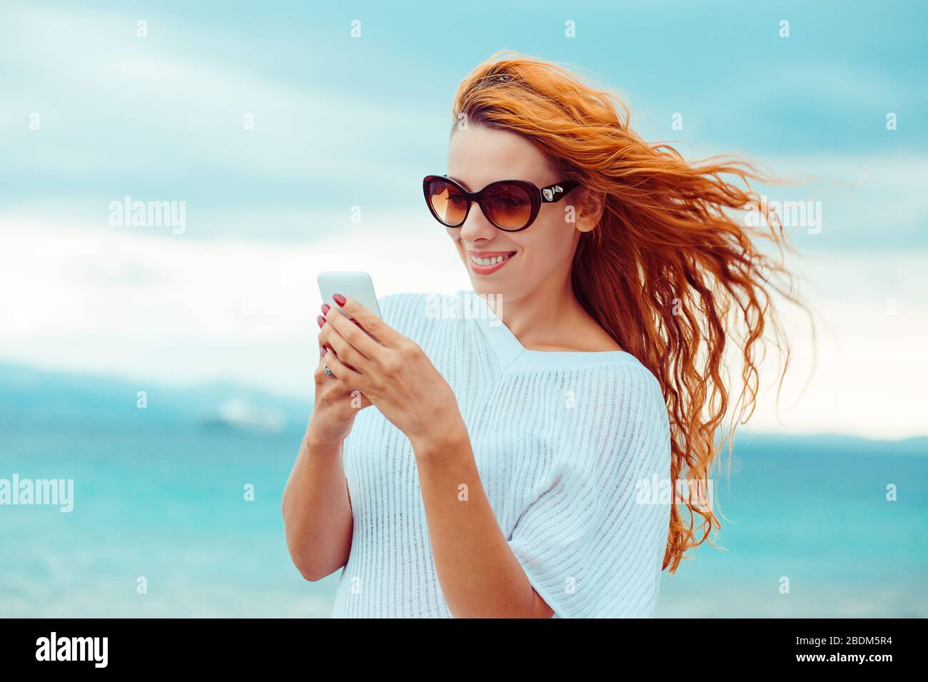 Donna felice in occhiali da sole che testano su uno smartphone sulla  spiaggia con il mare sullo sfondo. Effetto filtro Instagram applicato Foto  stock - Alamy