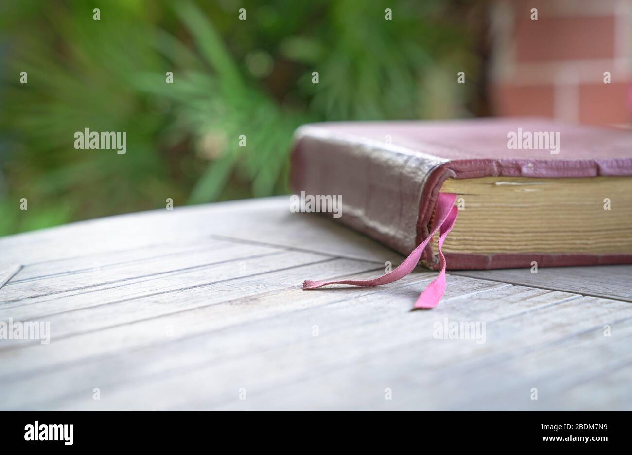 Sacra Bibbia con copertina marrone sul tavolo in legno. Sfocatura morbida con messa a fuoco sul marchio del libro in tessuto. Foto Stock