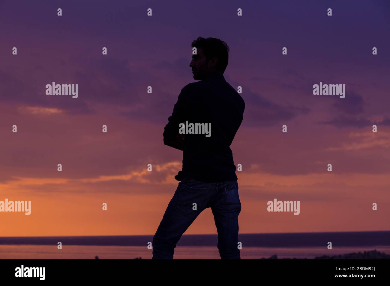 uomo d'affari in piedi di fronte al mare al tramonto, vista laterale profilo dell'uomo in piedi pensando al futuro sfondo all'aperto Foto Stock