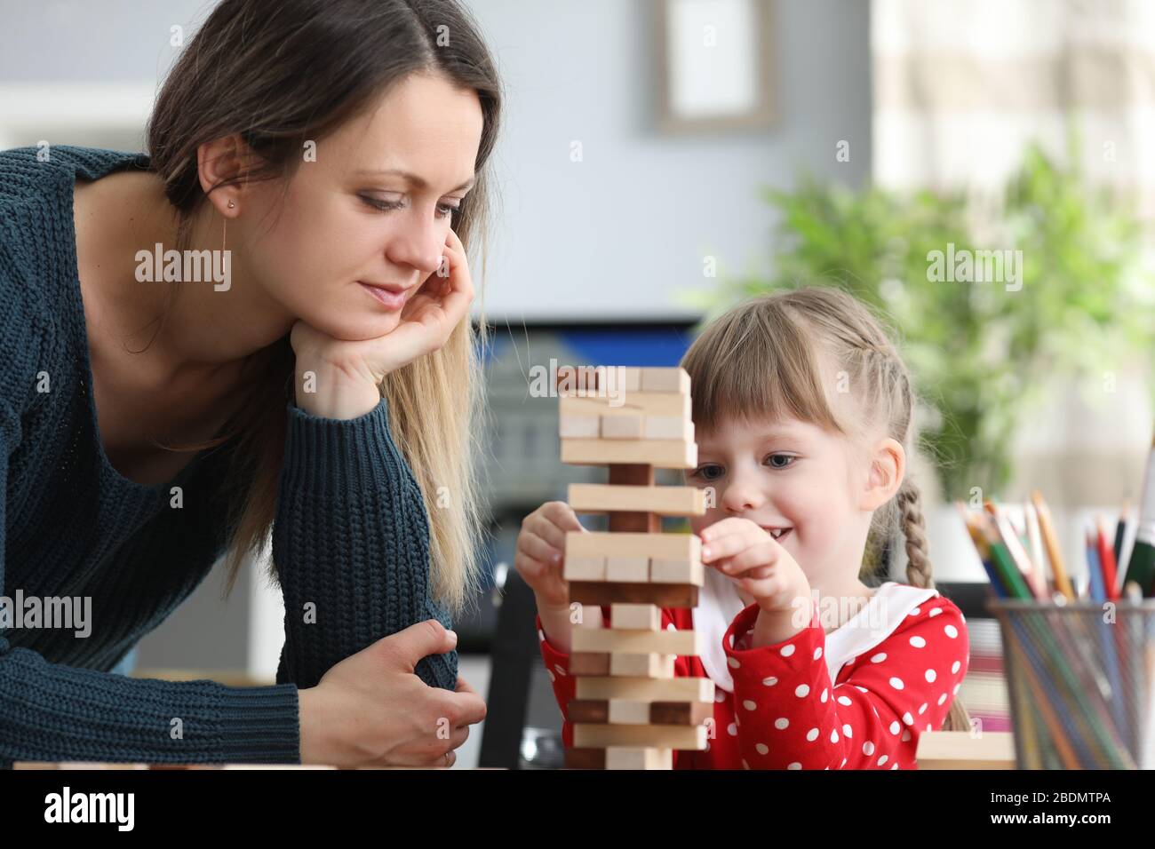Mamma aiuta pazientemente la sua figlia a costruire la struttura Foto Stock