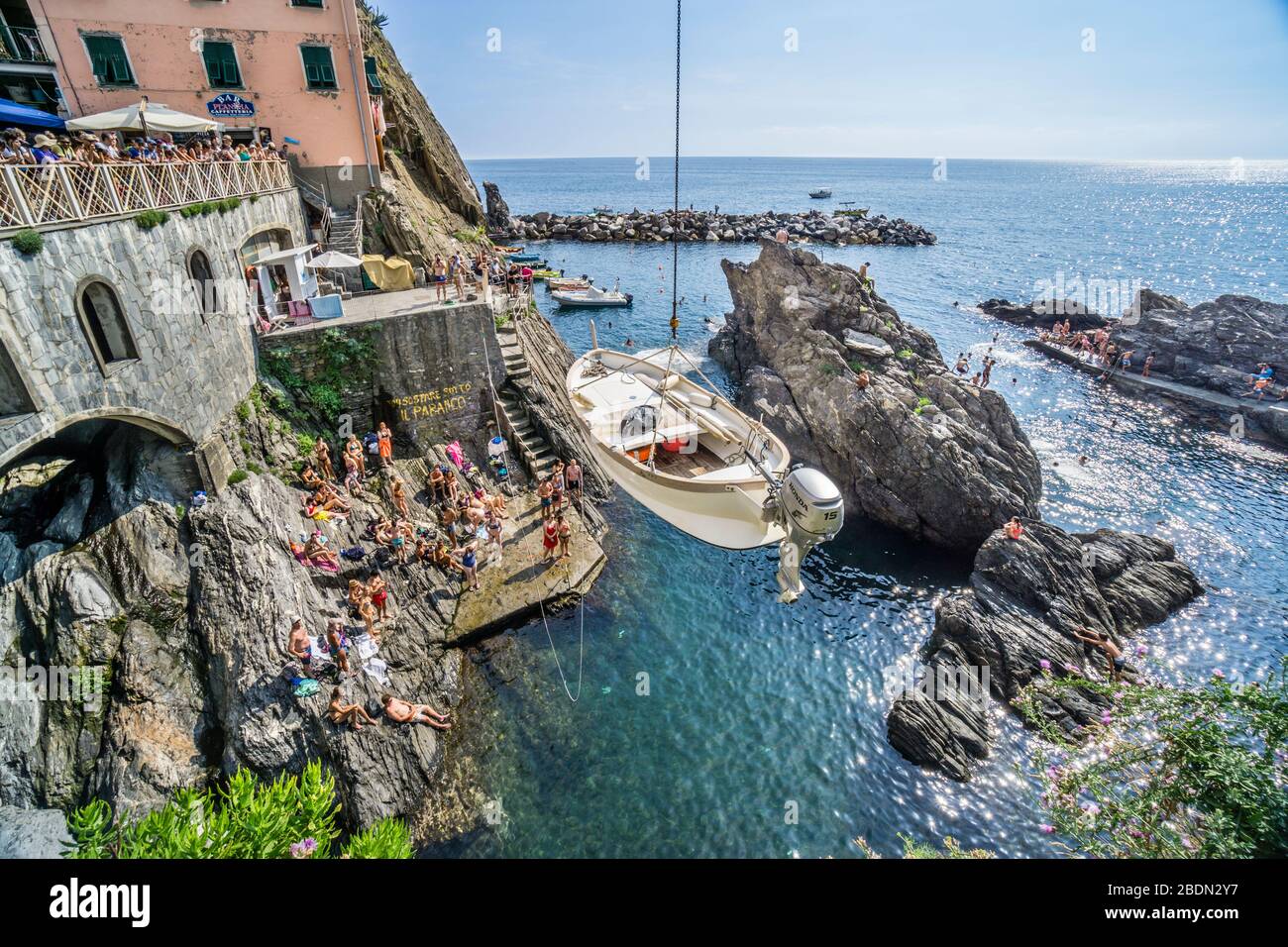 Una barca viene abbassata nel porto di Manarola, in mezzo alla roccia, nelle cinque Terre, Riviera ligure di Levante, Liguria, Italia Foto Stock