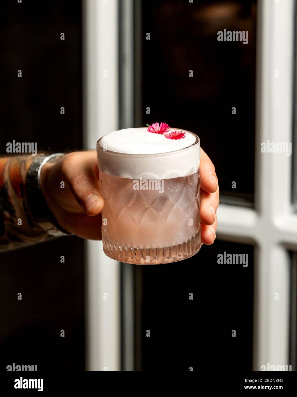 cocktail rosa con petali di schiuma e fiori Foto Stock