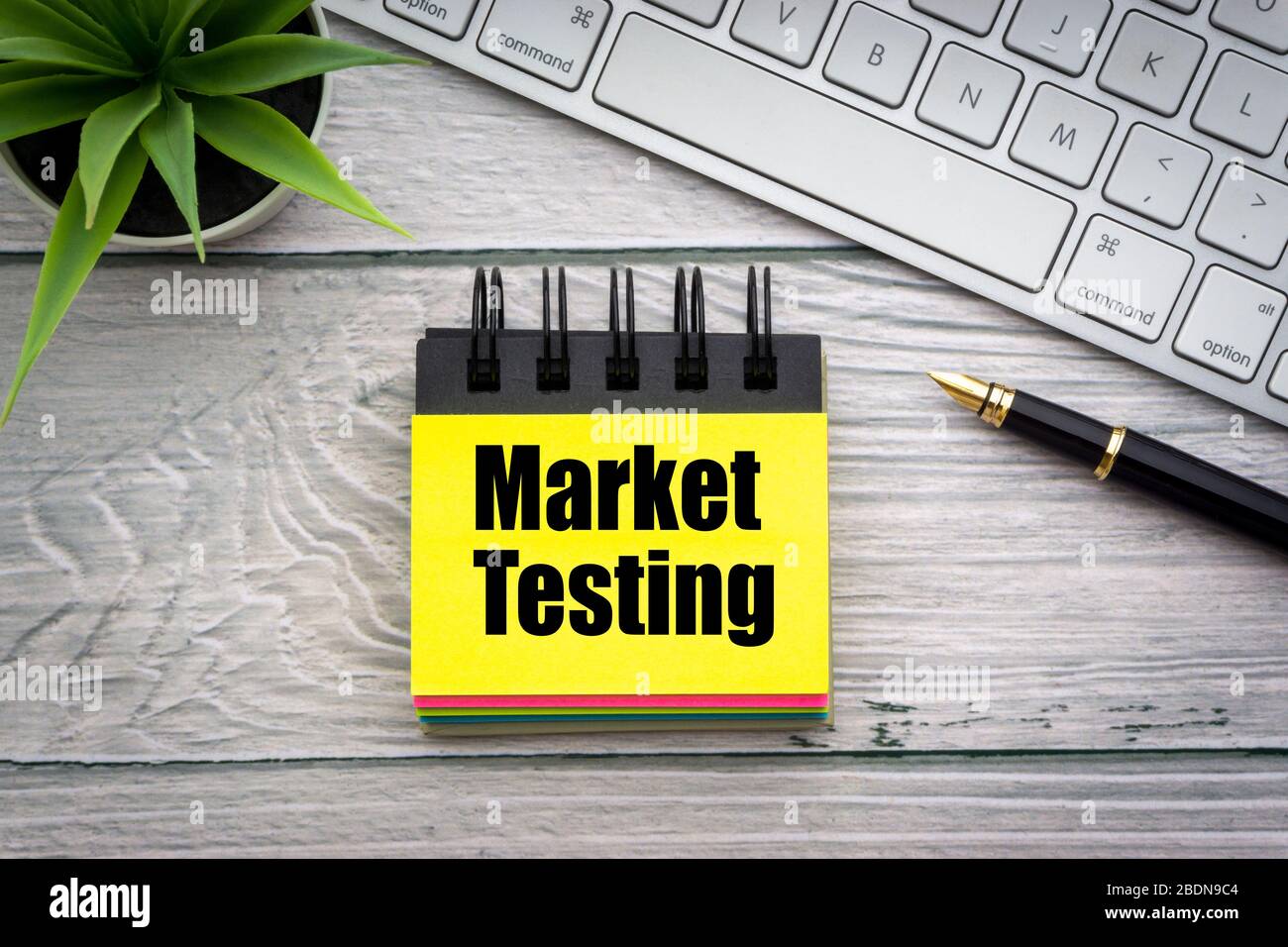 TESTO DI PROVA DEL MERCATO con fiore decorativo, penna stilografica, tastiera e blocco note su sfondo di legno. Concetto di business e tecnologia Foto Stock
