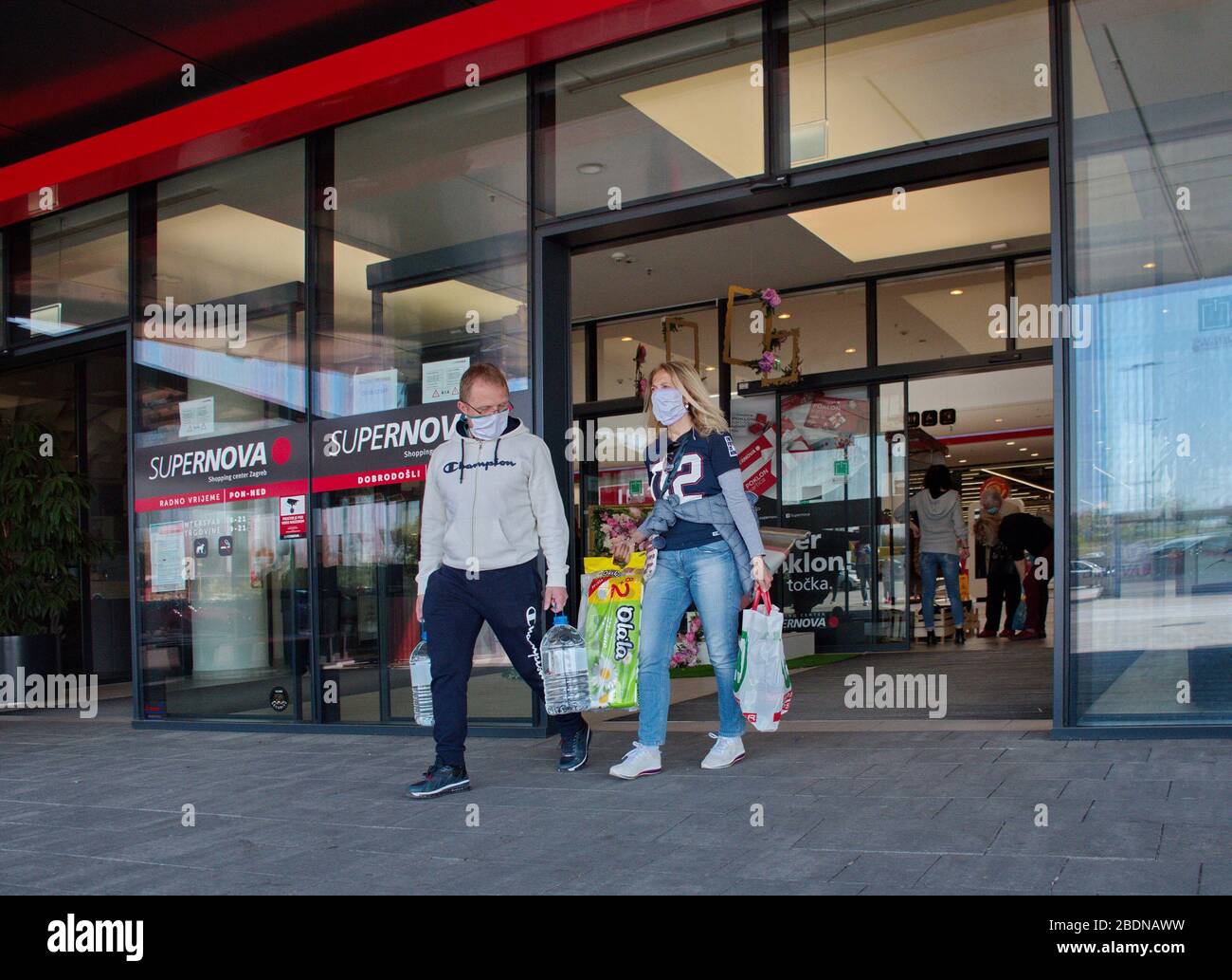 Coppia con la maschera di medicina che tiene i sacchetti di shopping uscendo dal centro commerciale Foto Stock