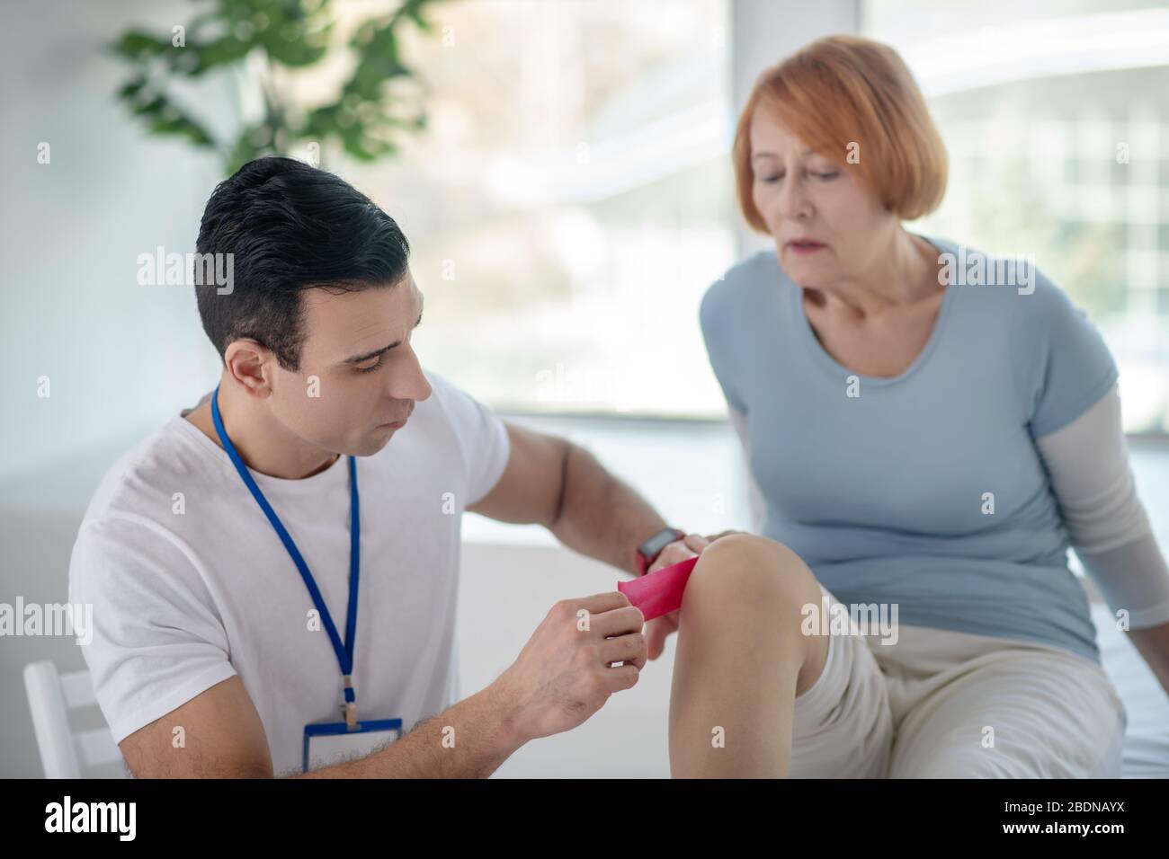 Medico intelligente dai capelli scuri che cura gli arti dei suoi pazienti Foto Stock