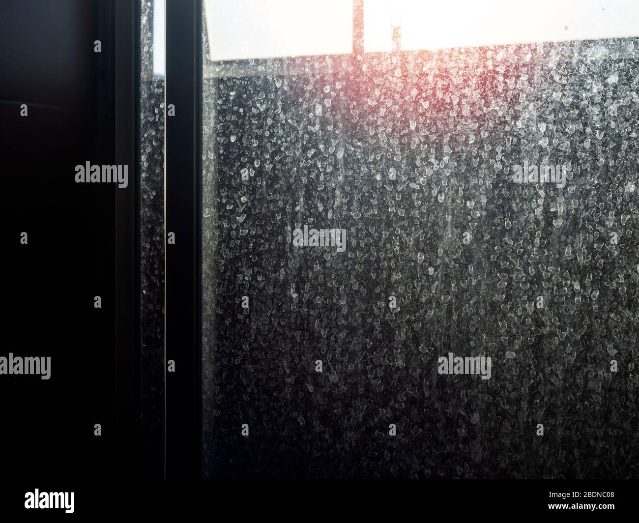Sportello in vetro sporco e polveroso. Macchia d'acqua sulla porta scorrevole in bagno, sfondo scuro. Foto Stock