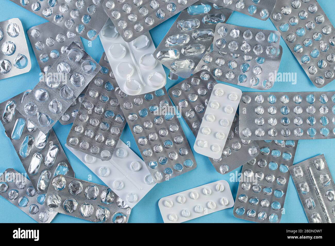 Un mucchio usato blister confezioni di pillole su sfondo blu. Blister per uso medico aperti e vuoti senza pillole vista dall'alto. Concetto medico e sanitario. Foto Stock