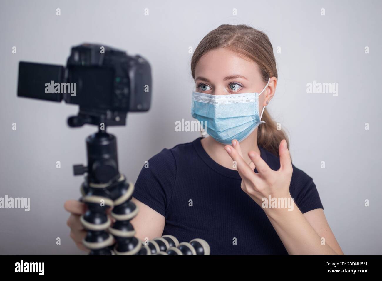 Sorridente giovane donna caucasica ragazza indossare maschera, facendo un video blog (vlog) con la macchina fotografica a casa Foto Stock