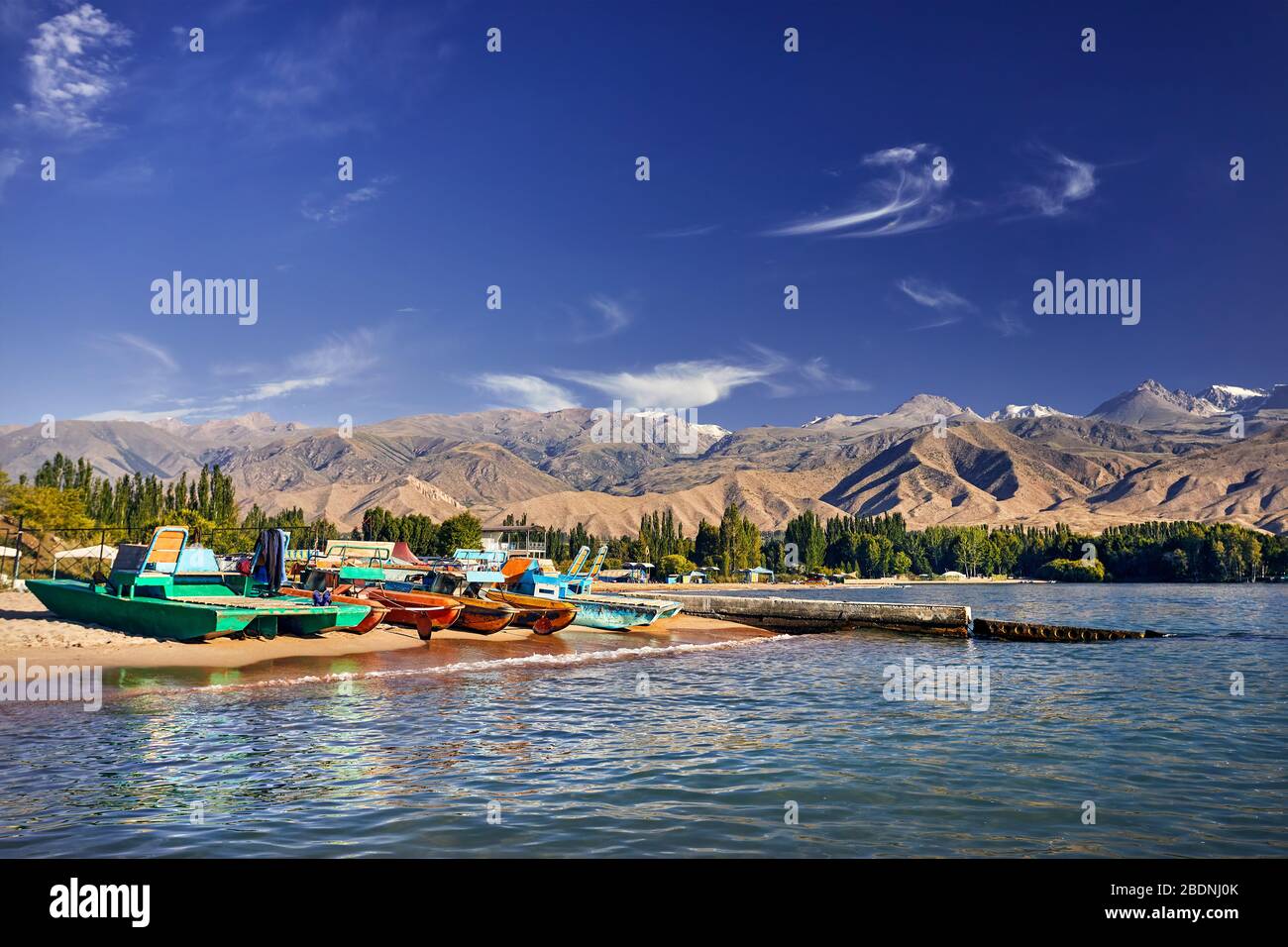 La colorata vecchia scuola di barche e catamarani sulla spiaggia di Issyk Kul Lago in Kirghizistan Foto Stock