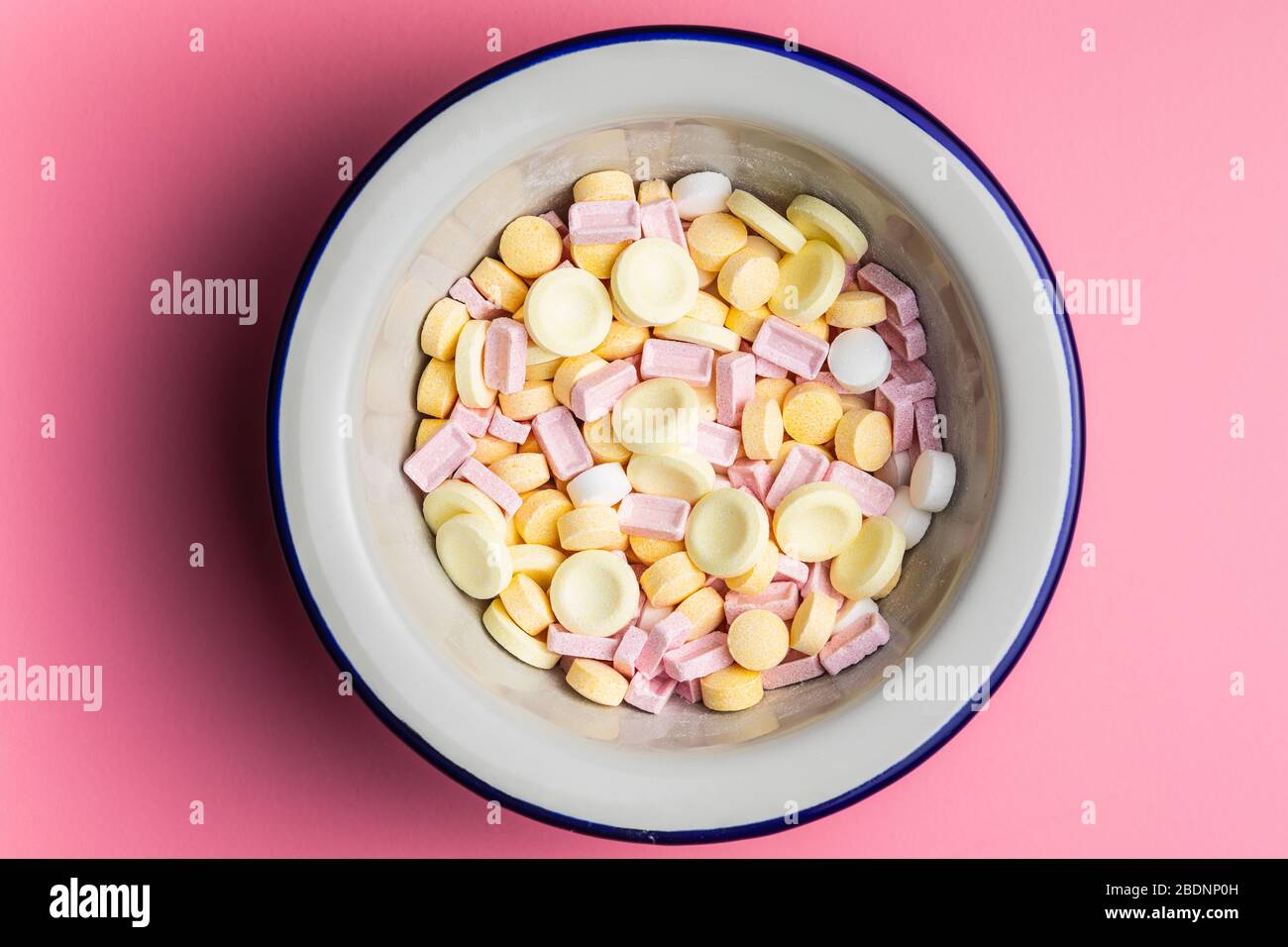 Mix di caramelle dure e colorate in ciotola su sfondo rosa. Vista dall'alto. Foto Stock
