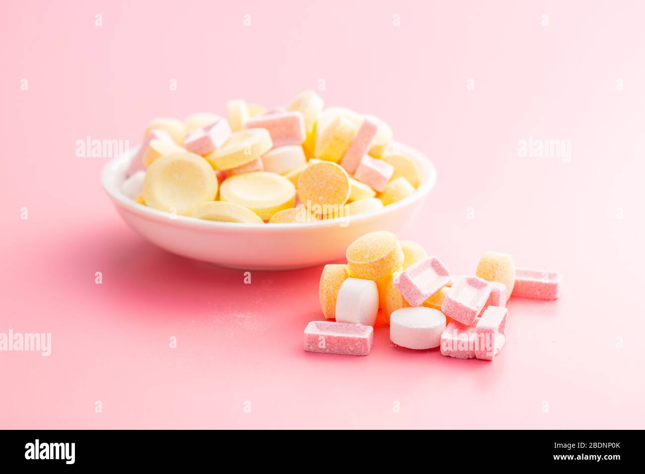 Mix di caramelle dure e colorate su sfondo rosa. Foto Stock