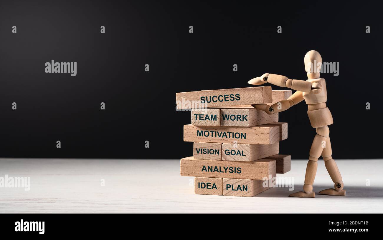 Uomo di legno costruisce la torre di mattoni lunghi di legno con le parole. Costruire il vostro futuro di successo. Concetto di successo, lavoro di squadra, motivazione, obiettivo di visione, un Foto Stock