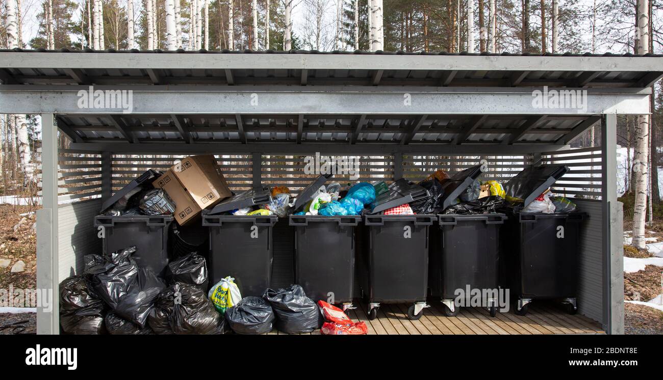 Contenitori per rifiuti domestici da 400 litri riempiti in modo eccessivo nel punto di raccolta dei rifiuti comune Foto Stock