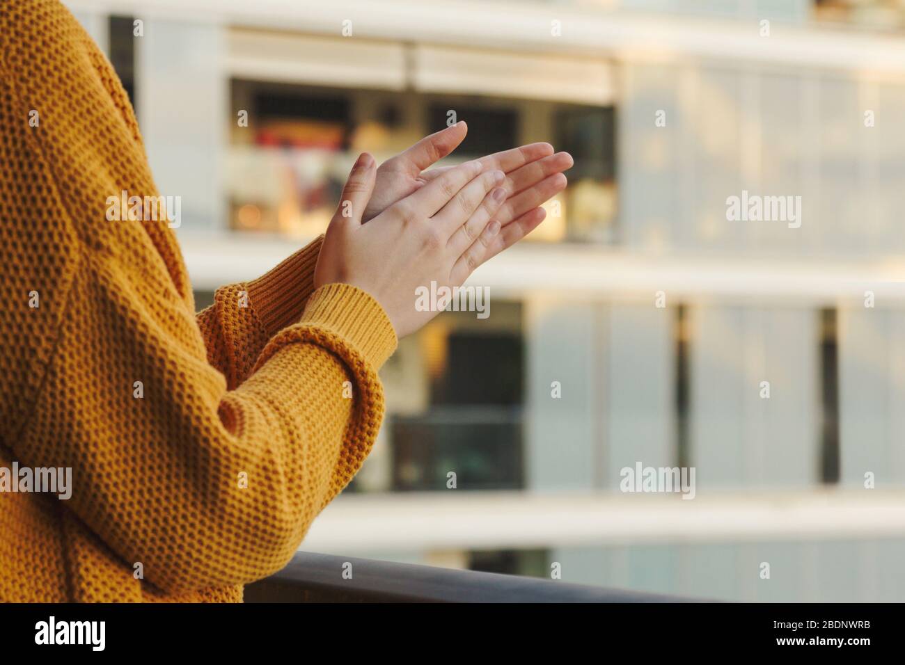 Foto di scorta delle mani di una ragazza applauding dal suo balcone per sostenere quelli che combattono coronavirus Foto Stock