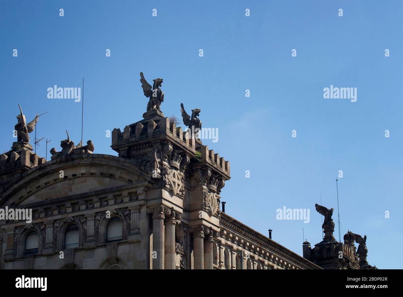 Da vicino si può ammirare la storica scultura di leoni alati sulla cima del vecchio edificio di Barcellona. È una giornata estiva soleggiata. Foto Stock