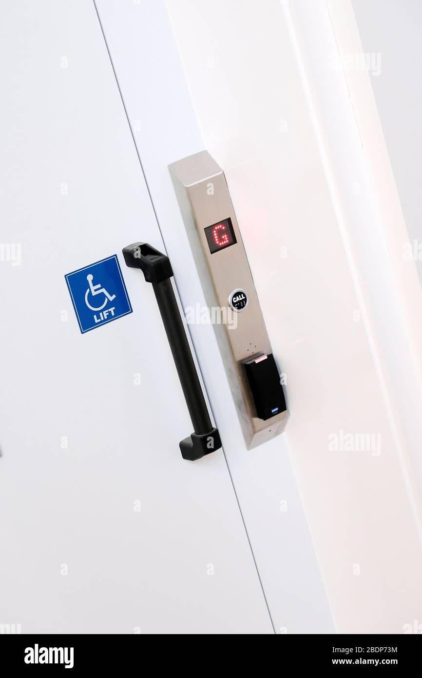 una porta di sollevamento chiusa che mostra un'etichetta di disattivazione e una luce del piano terra illuminata Foto Stock